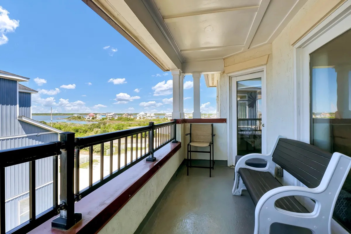 A private balcony overlooking lush landscaping with outdoor seating visible. The scene is tranquil and inviting, perfect for morning coffee, sunset conversations, or group brunches while enjoying the view.
