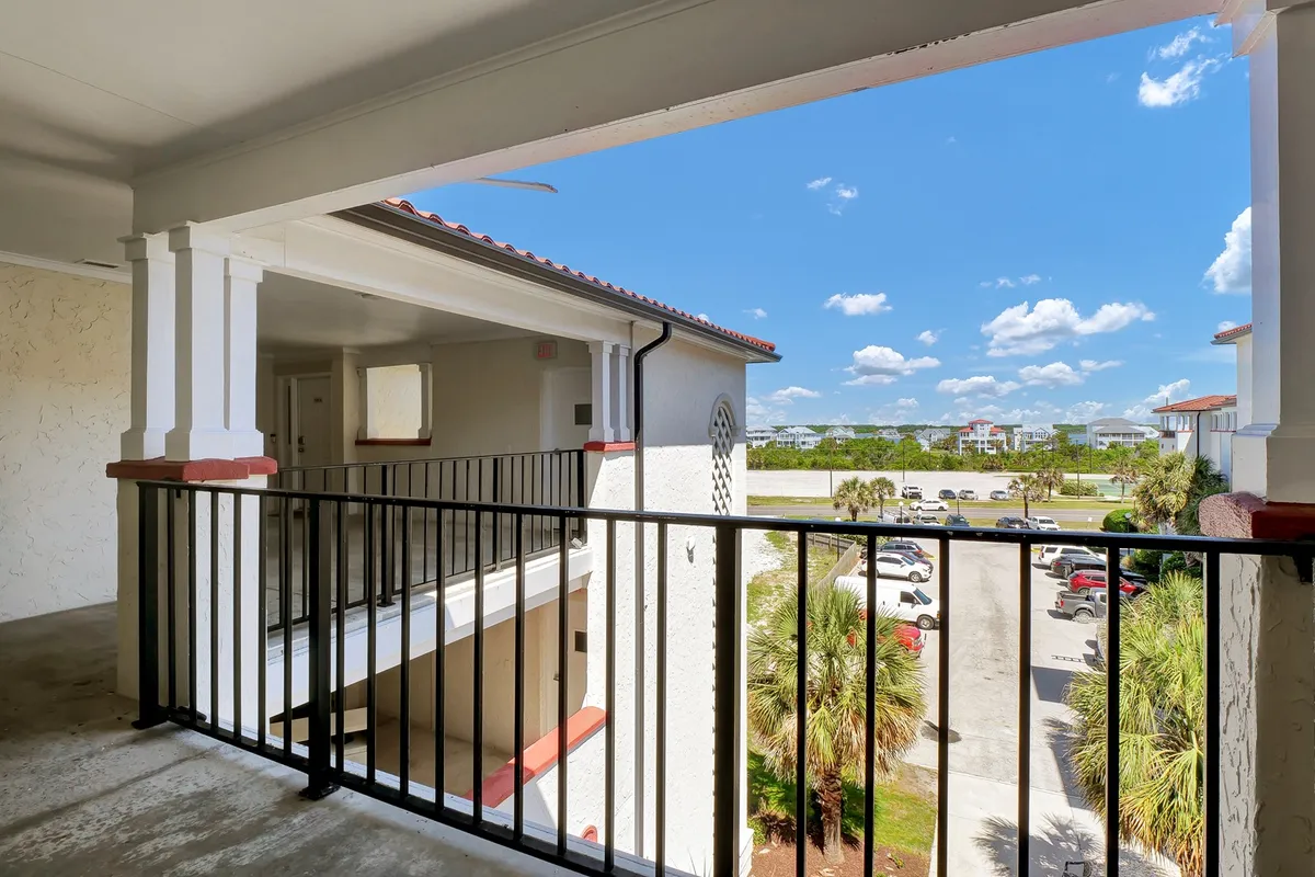 A private balcony overlooks the lush landscape with the blue sky and clouds above. The balcony’s railing frames a tranquil setting ideal for enjoying morning coffee, reading in the fresh air, or watching the sunset over the ocean.